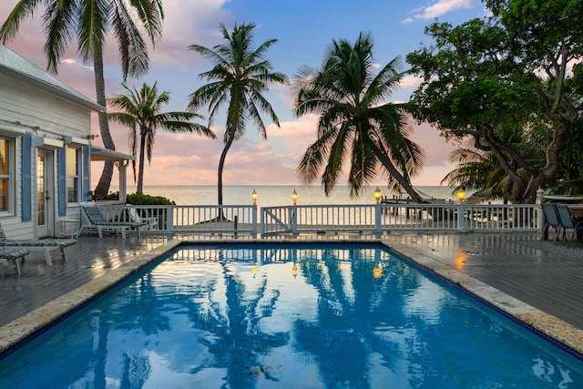 pool at dusk featuring a water view