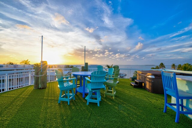 yard at dusk with a hot tub and a water view