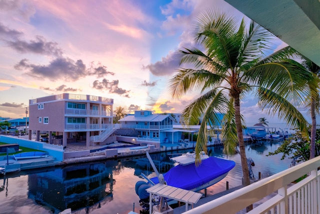 pool at dusk with a water view and a dock