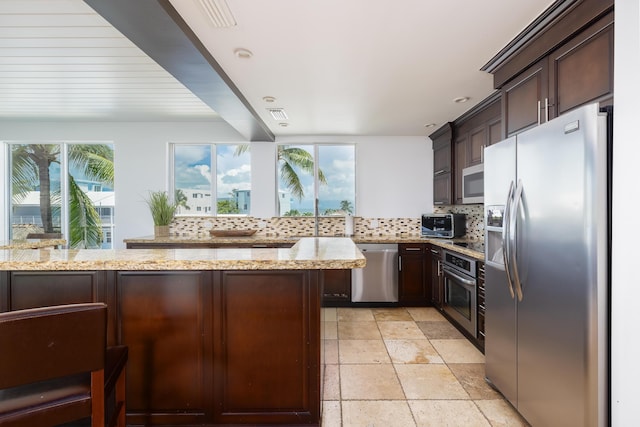 kitchen with stainless steel appliances, light stone countertops, kitchen peninsula, and decorative backsplash