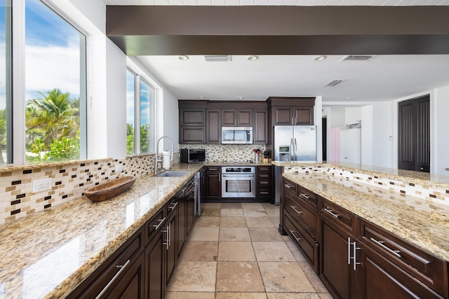 kitchen with sink, stainless steel appliances, dark brown cabinetry, light stone countertops, and decorative backsplash