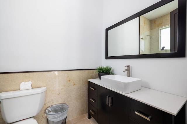 bathroom featuring walk in shower, vanity, toilet, and tile walls