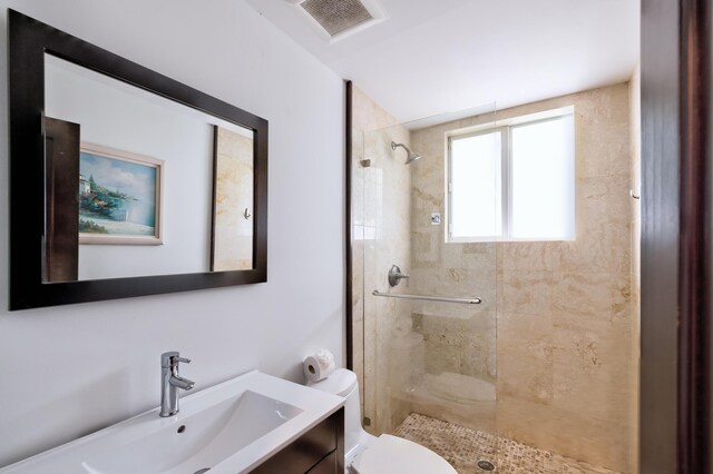 bathroom with vanity, toilet, and tiled shower