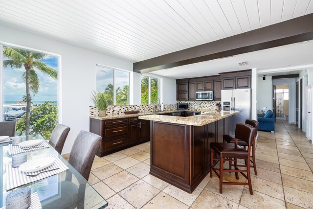 kitchen featuring tasteful backsplash, appliances with stainless steel finishes, a healthy amount of sunlight, and a breakfast bar area