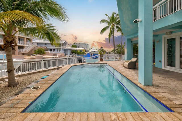 pool at dusk featuring a patio area