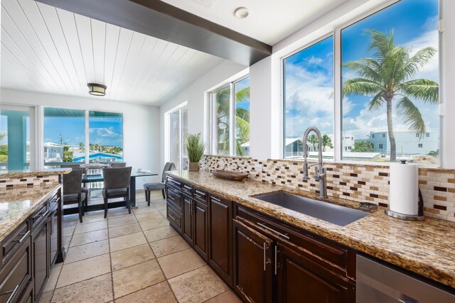 kitchen featuring dark brown cabinetry, sink, wood ceiling, light stone countertops, and decorative backsplash