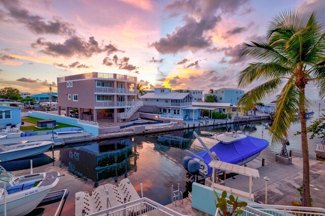 pool at dusk with a water view and a dock