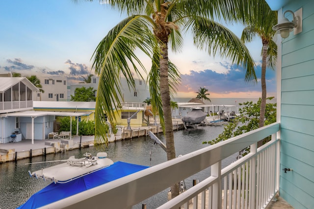 balcony at dusk featuring a water view