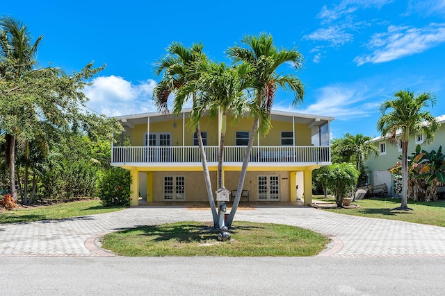 raised beach house featuring a front yard and french doors