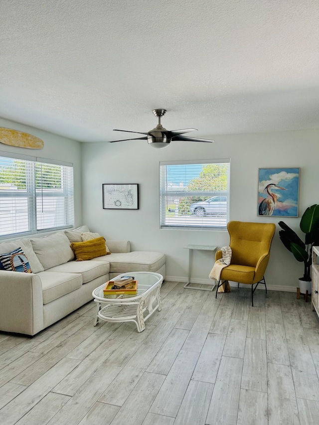 living room featuring ceiling fan, light hardwood / wood-style floors, and a textured ceiling