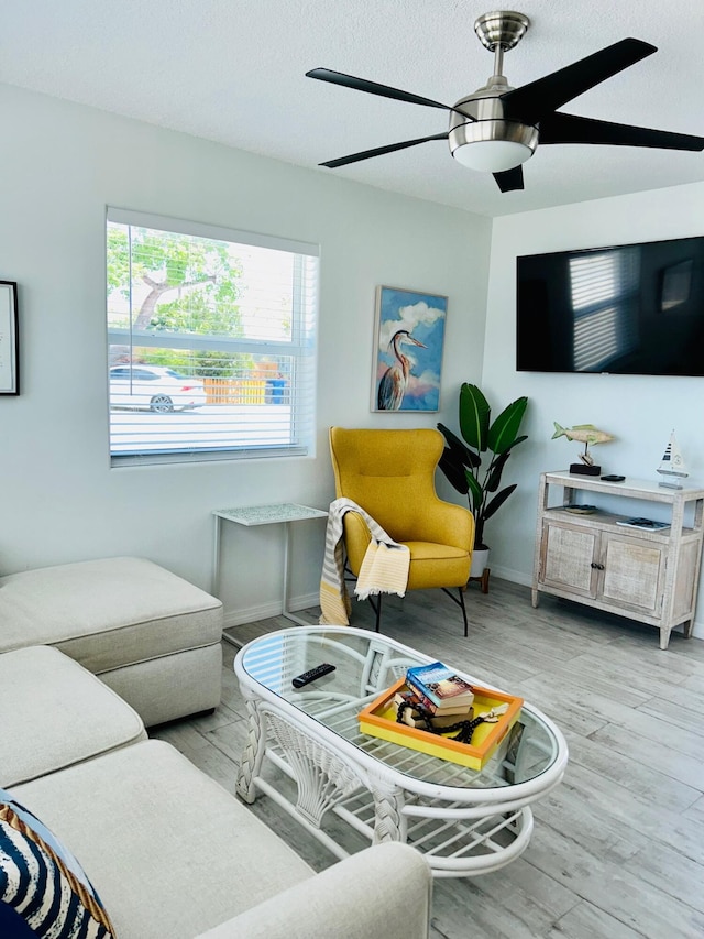 living room with a textured ceiling, light hardwood / wood-style flooring, and ceiling fan