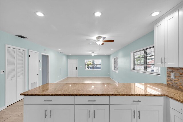 kitchen featuring white cabinetry, ceiling fan, stone countertops, and light tile patterned flooring