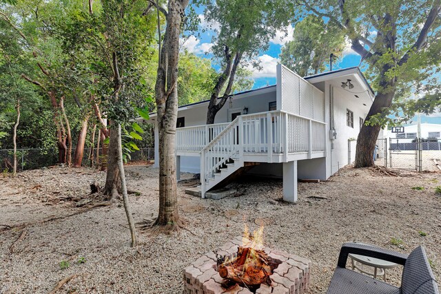 rear view of house with a wooden deck and a fire pit