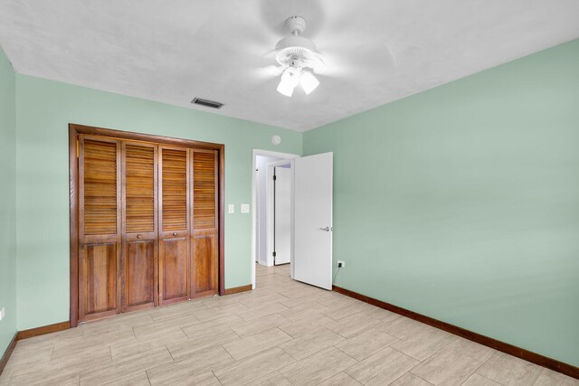 unfurnished bedroom featuring ceiling fan and a closet