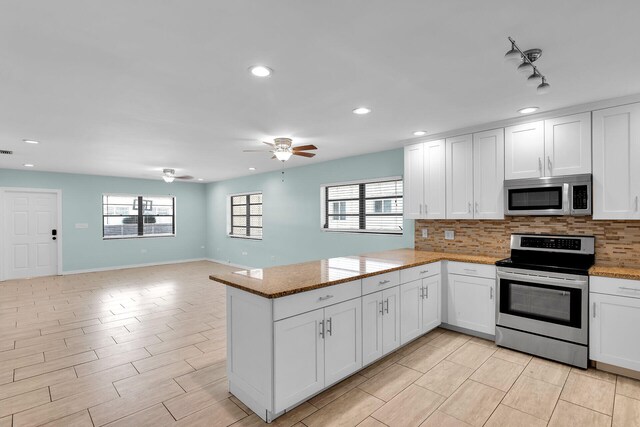 kitchen with stainless steel appliances, white cabinets, backsplash, and kitchen peninsula