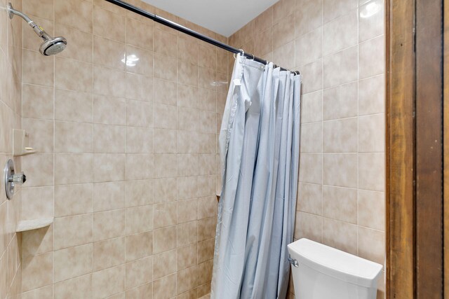 bathroom featuring toilet, tile walls, and a shower with shower curtain