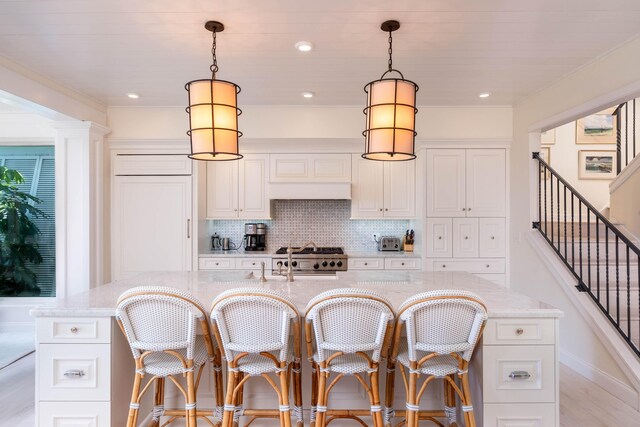81250 Overseas Hwy Unit 5, Islamorada, FL 33036 - kitchen with white cabinetry, light stone countertops, hanging light fixtures, and a center island with sink
