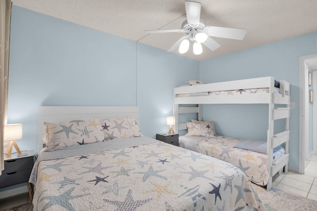 tiled bedroom with ceiling fan and a textured ceiling