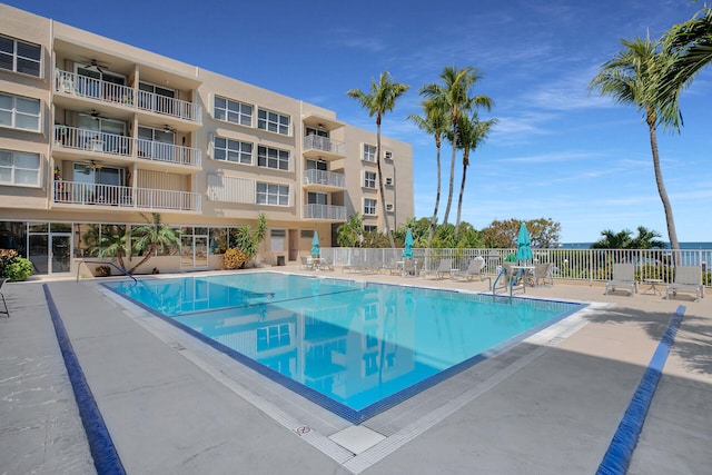 community pool with a patio area, fence, and a ceiling fan