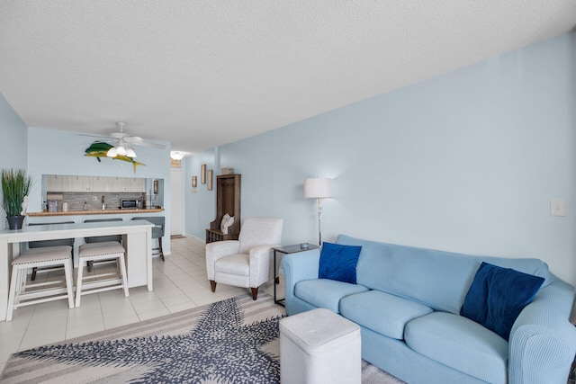 living room featuring ceiling fan, a textured ceiling, and light tile patterned flooring