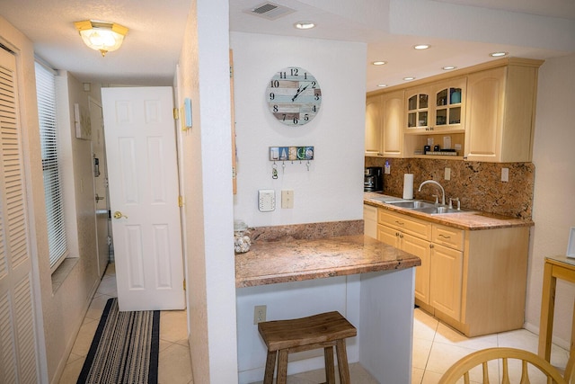 104350 Overseas Hwy Unit B205, Key Largo, FL 33037 - kitchen with light brown cabinetry, light tile patterned floors, backsplash, glass insert cabinets, and a breakfast bar