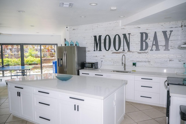 104350 Overseas Hwy Unit B205, Key Largo, FL 33037 - kitchen with appliances with stainless steel finishes, light tile patterned flooring, light countertops, a center island, and white cabinetry