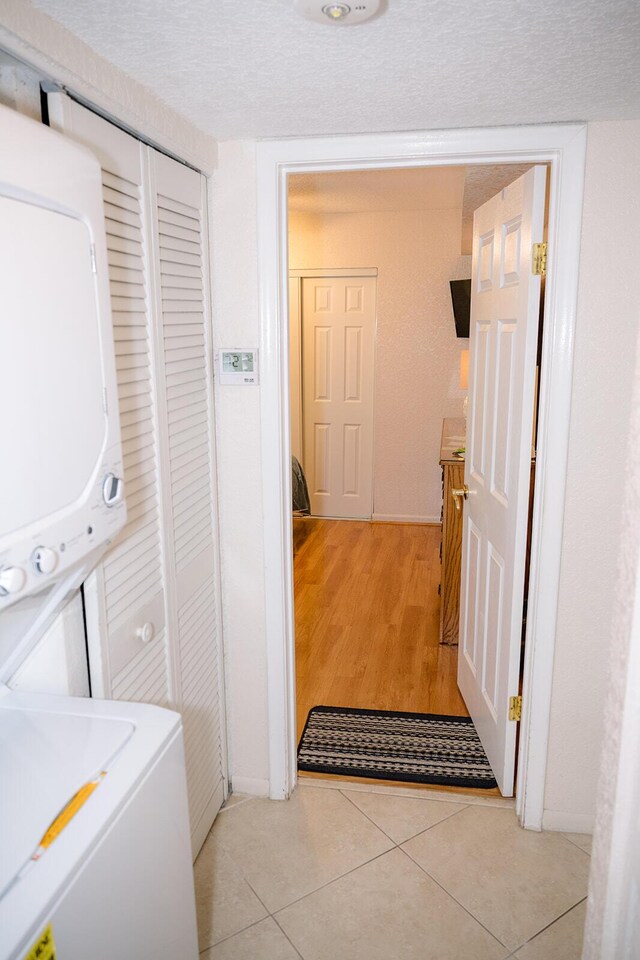 104350 Overseas Hwy Unit B205, Key Largo, FL 33037 - laundry room featuring estacked washer and dryer, a textured ceiling, and light tile patterned flooring