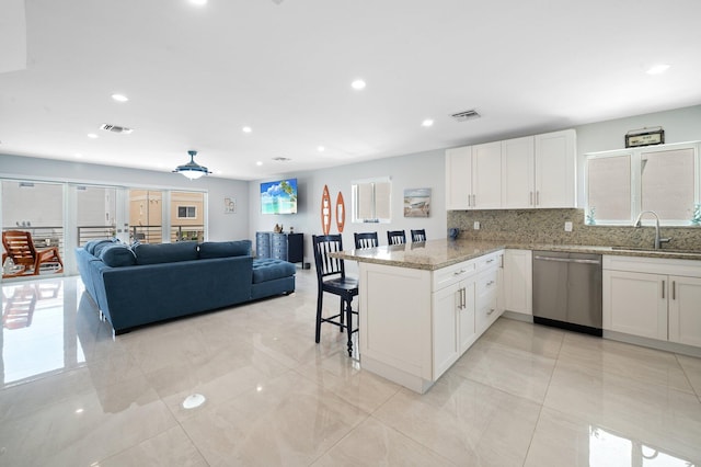 94825 Overseas Hwy Unit 185, Key Largo, FL 33037 - kitchen featuring dishwasher, a peninsula, light stone countertops, white cabinetry, and backsplash