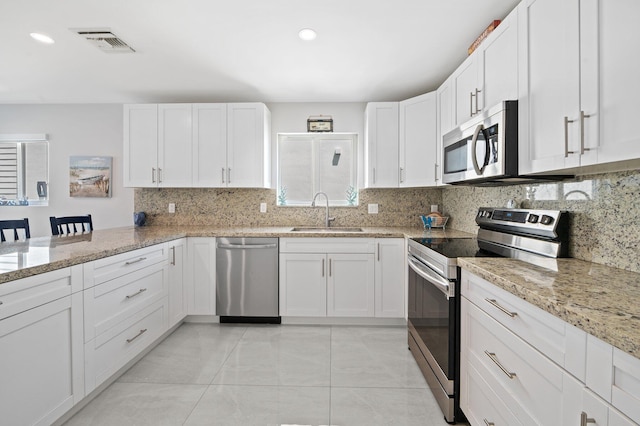 94825 Overseas Hwy Unit 185, Key Largo, FL 33037 - kitchen with appliances with stainless steel finishes, decorative backsplash, white cabinetry, light stone countertops, and recessed lighting