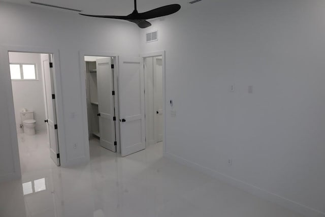 unfurnished bedroom with a walk in closet, connected bathroom, ceiling fan, and a closet