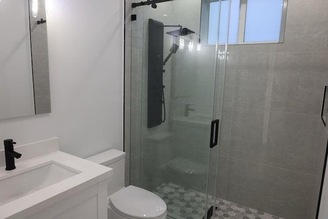 bathroom featuring vanity, toilet, and a shower with door