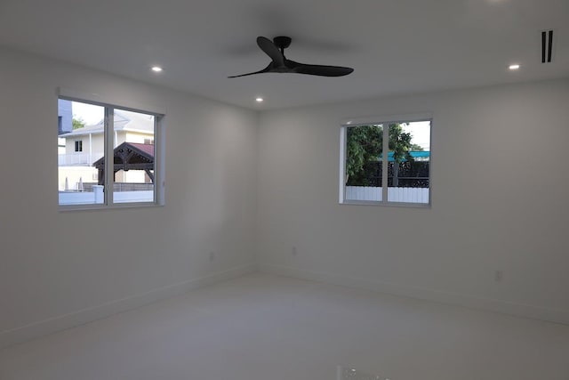 empty room with plenty of natural light, concrete flooring, and ceiling fan