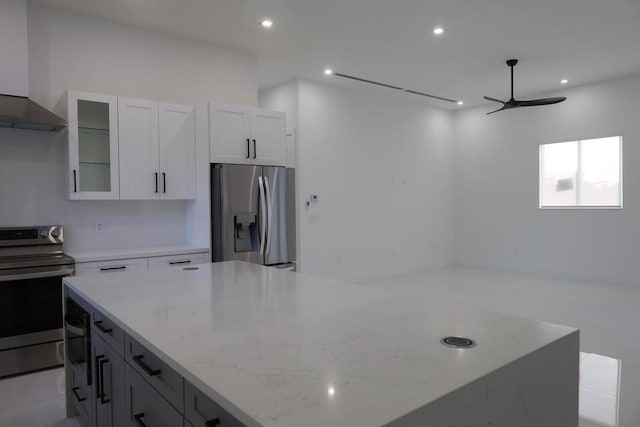 kitchen with light stone counters, white cabinetry, wall chimney exhaust hood, and appliances with stainless steel finishes