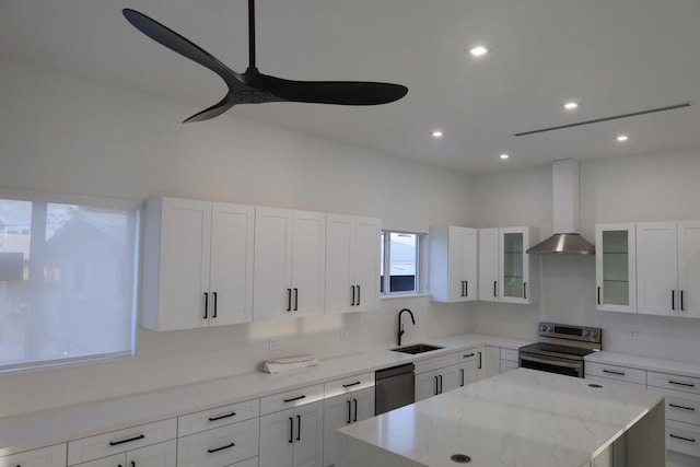 kitchen with sink, dishwasher, stainless steel range with electric stovetop, a kitchen island, and wall chimney exhaust hood