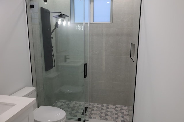 bathroom featuring vanity, a shower with shower door, and toilet