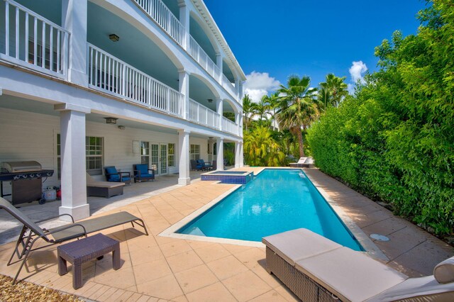 view of pool with an in ground hot tub, grilling area, and a patio