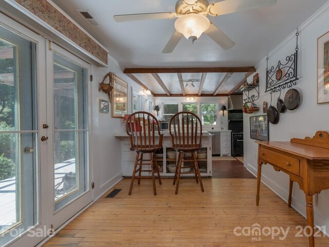 dining space featuring ceiling fan, a wealth of natural light, beamed ceiling, and light hardwood / wood-style floors