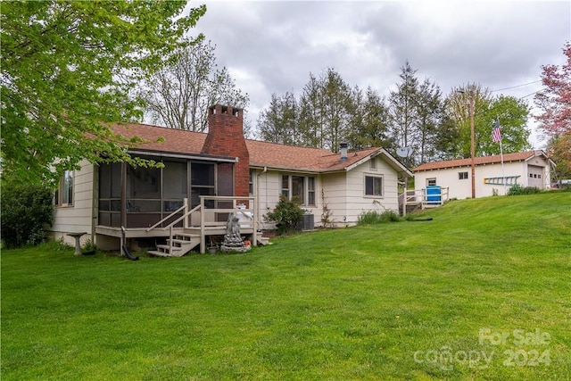 rear view of house featuring central AC, a sunroom, and a lawn