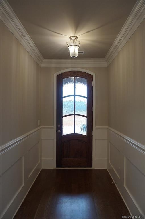 doorway to outside with crown molding and dark wood-type flooring