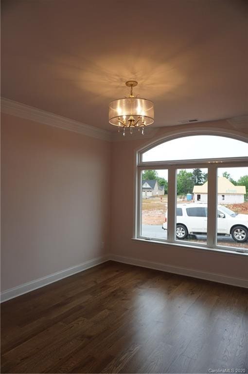 empty room featuring french doors, ornamental molding, a notable chandelier, and dark wood-type flooring