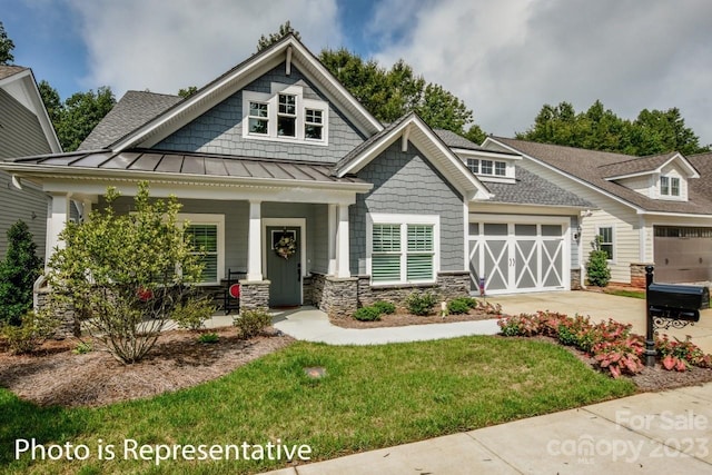 view of front of home with a porch, a front yard, and a garage