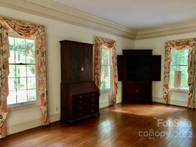 unfurnished living room with ornamental molding and dark hardwood / wood-style floors