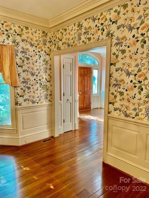 empty room featuring plenty of natural light, ornamental molding, and dark hardwood / wood-style floors