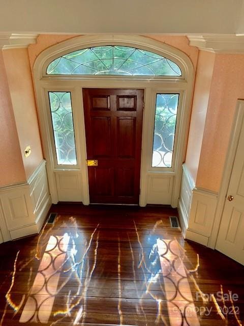 foyer entrance featuring crown molding and dark wood-type flooring