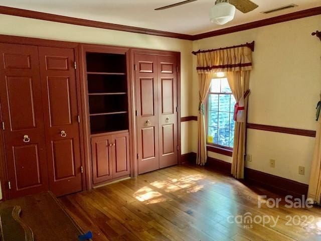 unfurnished bedroom with crown molding, ceiling fan, and dark wood-type flooring