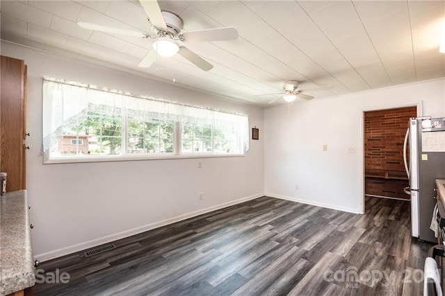 empty room featuring ceiling fan, dark wood-type flooring, and a wealth of natural light