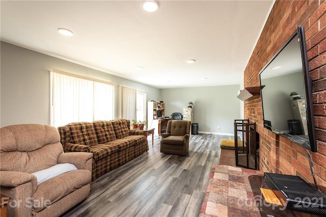 living room featuring a brick fireplace, brick wall, and dark hardwood / wood-style floors