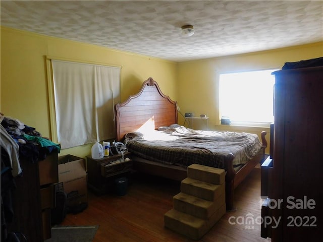 bedroom with dark hardwood / wood-style flooring and a textured ceiling