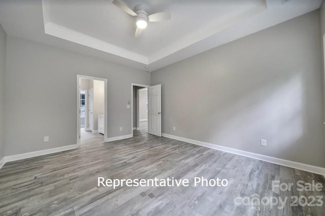 unfurnished room with wood-type flooring, ceiling fan, and a raised ceiling