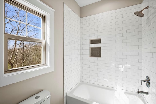 bathroom featuring toilet and tiled shower / bath